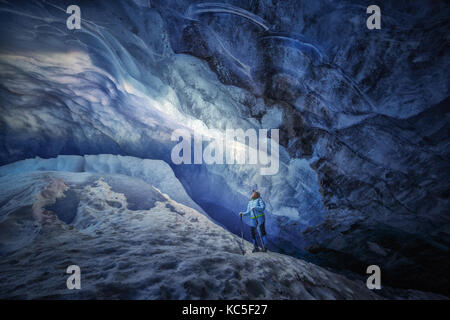 Explorer girl inside an ice cave during a photography expedition in Athabasca Glacier Stock Photo