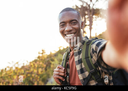 Smiling young African man taking a selfie while hiking outdoors Stock Photo