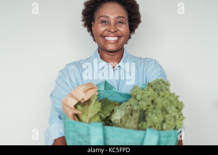 Smiling young African woman holding a bag of groceries Stock Photo