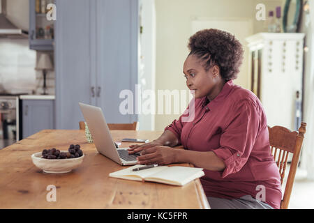 Young African woman sitting at home working on a laptop Stock Photo