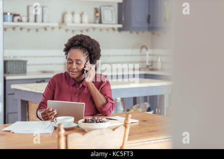 Smiling woman using a tablet and talking on the phone Stock Photo