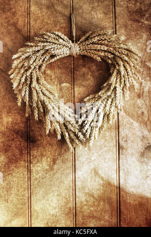 Decorative grain wreath against a wooden panelled door. Textured grunge layer appled for grunge rustic effect. Stock Photo