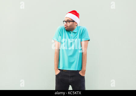 Christmas problem. Flying of thoughts. Thoughtful bearded businessman looking away while standing against  gray wall. Studio shot Stock Photo