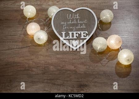 Decorative heart with text and multicolour lights on the wooden table Stock Photo