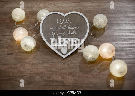 Decorative heart with text and multicolour lights on the wooden table Stock Photo