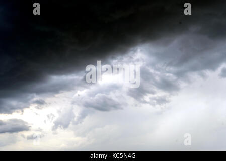 Stormy clouds in the sky with shades of black and grey and fragments and wisps of rain Stock Photo