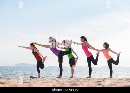 Yoga class at sea beach in evening ,Group of people doing Lord of the Dance poses with clam relax emotion at beach,Meditation pose,Wellness and Health Stock Photo