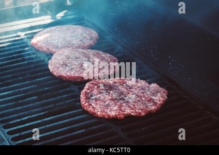 Burgers for the hamburger on Grill with Flames Cooked to Perfection. Meat beef on the grill Stock Photo