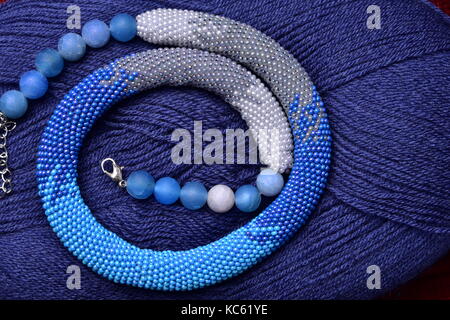 knitted flagellum from beads on a background of blue threads Stock Photo