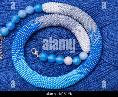 knitted flagellum from beads on a background of blue threads Stock Photo