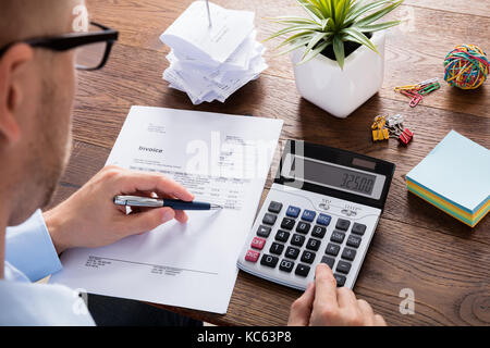 Accountant Or Financial Advisor Calculating Tax Using Calculator And Business Invoice On Wooden Desk Stock Photo
