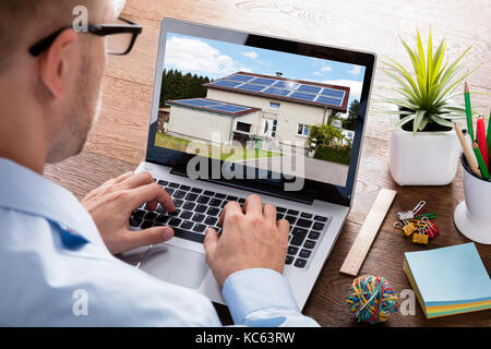 Close-up Of A Businessman Looking At Photo Of A House Online On Laptop Computer