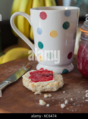 Scone with raspberry jam and spotty mug Stock Photo