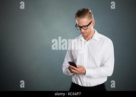 Businessman Using Mobile Phone Against Grey Background Stock Photo