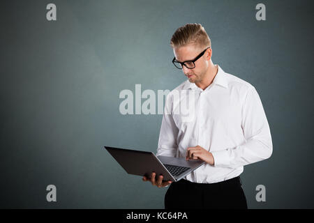 Businessman Using Laptop Computer Against Grey Background Stock Photo