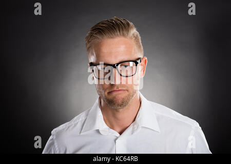 Portrait Of A Sad Thoughtful Young Man Against Black Background Stock Photo