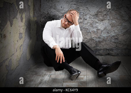 Young Worried Man Sitting In Abandoned Room Stock Photo