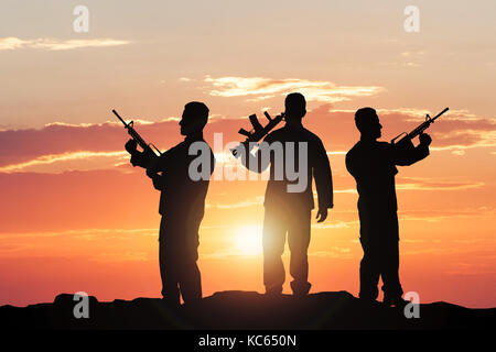 Silhouette Of Soldiers With Rifles Against Dramatic Sky