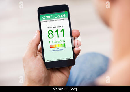 Man Holding Smart Phone Showing Credit Score Application On A Screen Stock Photo