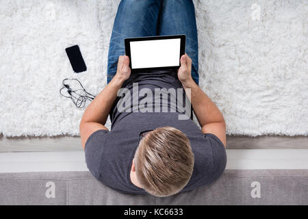 Man Sitting On White Carpet Using Digital Tablet Stock Photo
