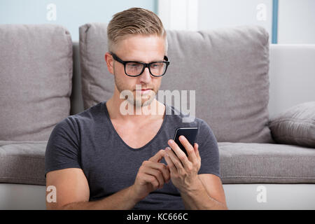 Young Man Using Smart Phone At Home Stock Photo