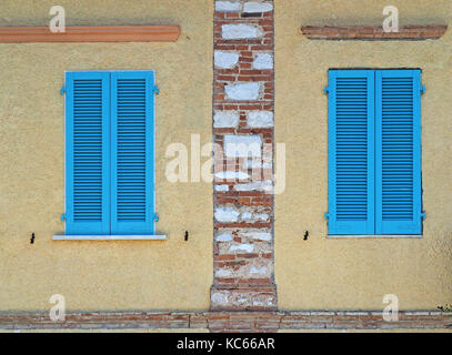 residential building with traditional wooden shutters painted bright blue in Tuscany, Italy Stock Photo