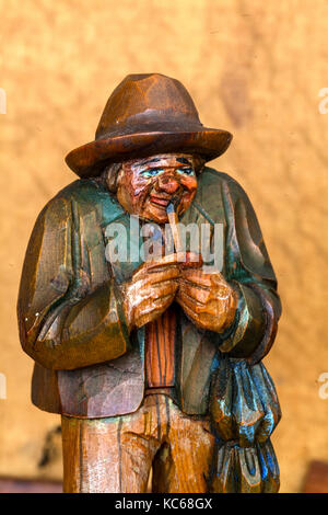 Antique wooden statue of happy old man smoking his pipe Stock Photo