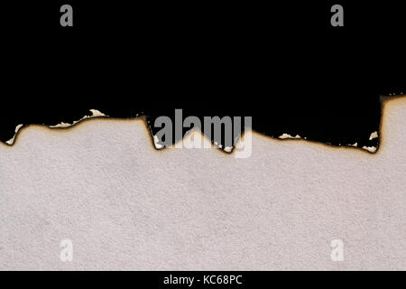 Burnt, burned and charred white paper on black background, showing ashes and burn lines Stock Photo