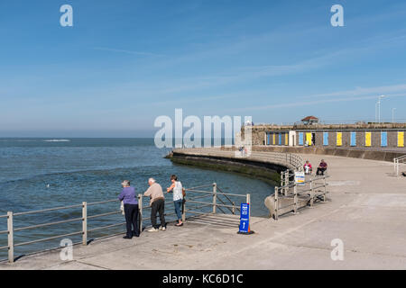 Minnis Bay, UK - SEP 24 2017. Tourists and locals on the promenade near the beach huts in Minnis Bay, Brichington. On the Isle of Thanet, kent, UK. Stock Photo