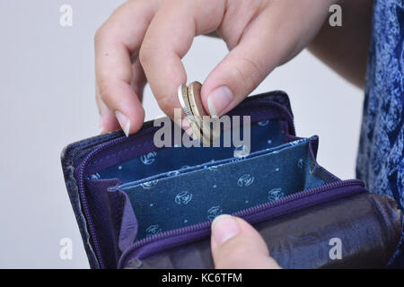 Woman taking out, or putting money into, a purse Stock Photo
