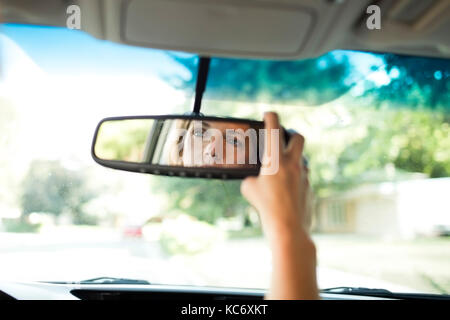 Woman adjusting rear-view mirror in car Stock Photo