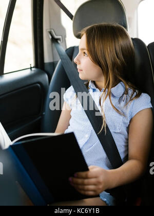 Girl ( 8-9) sitting in car and looking through window Stock Photo