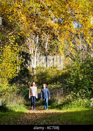 Australia, Queensland, Girls (10-11, 12-13) walking on footpath at autumn Stock Photo