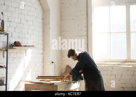 Professional carpenter using power hand saw in workshop, side vi Stock Photo