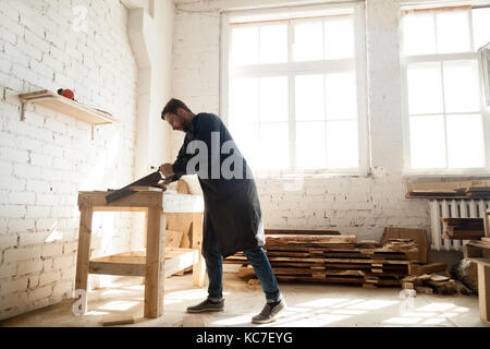 Woodwork and construction. Carpenter using handsaw for sawing wo Stock Photo