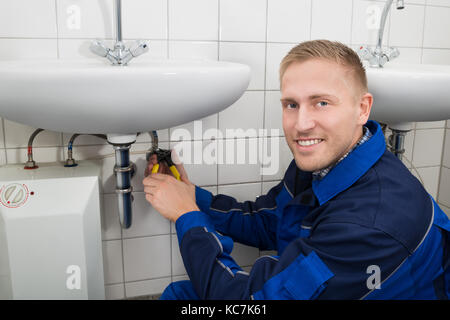 Photo Of Male Plumber Fixing Sink In Bathroom Stock Photo