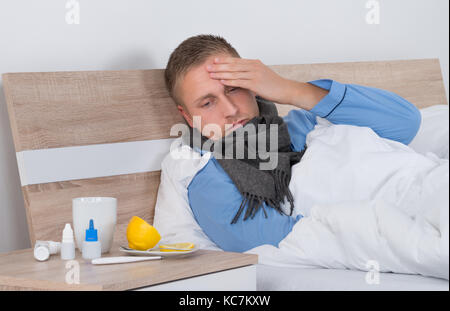 Young Man Suffering From Headache Lying On Bed Stock Photo