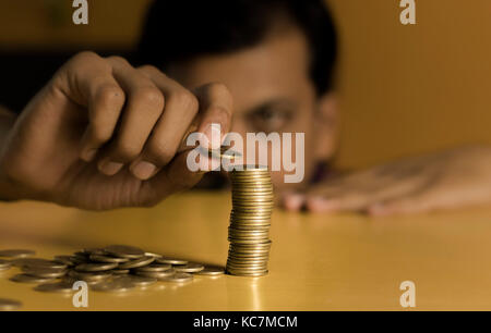 A man counting his coins placed on table Stock Photo