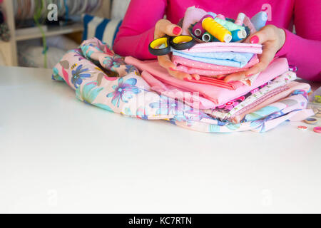 Female hands and accessories for sewing. Buttons, fabric and thread. Stock Photo