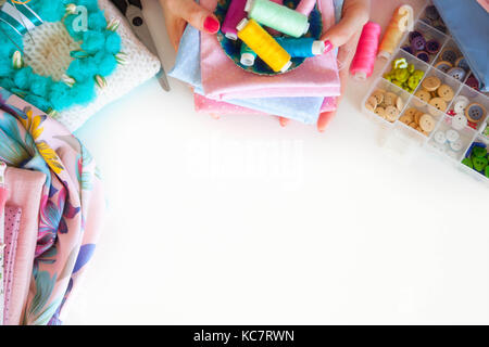 Female hands and accessories for sewing. Buttons, fabric and thread. Stock Photo