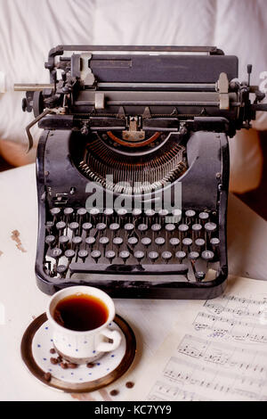 Old metal typewriter, covered in dust and rust.Cup of coffee on the table. The atmosphere of comfort and creativity. Retro Stock Photo
