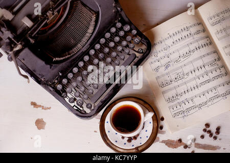 Old metal typewriter, covered in dust and rust.Cup of coffee on the table. The atmosphere of comfort and creativity. Retro Stock Photo