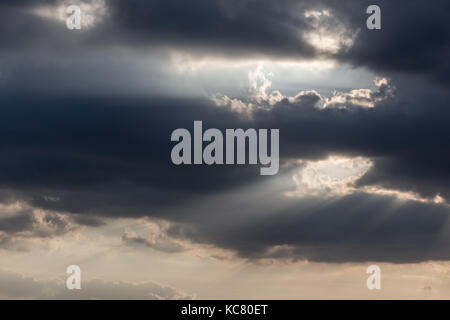 Powerful sun rays coming out through some dark clouds Stock Photo