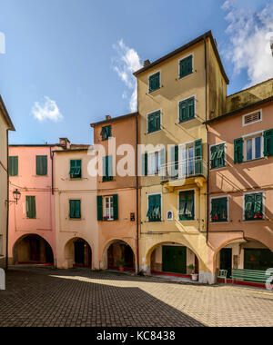 foreshortening of little round square among old picturesque bending houses with covered walkway, shot in bright late summer light at Varese Ligure, Ge Stock Photo