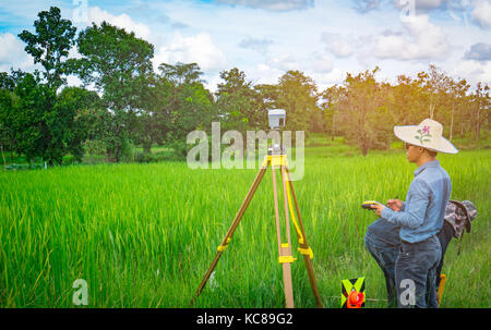 UBONRATCHATHANI, THAILAND-SEPTEMBER 26, 2017 : Asian smart engineer or surveyor is working on controller screen for surveying land in rice field. GPS  Stock Photo