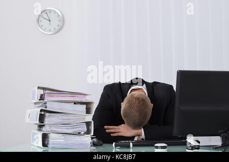 Young Male Businessman Sleeping On Desk In Office Stock Photo