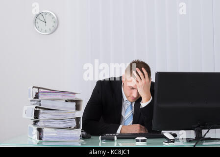 Young Male Businessman Sleeping On Desk In Office Stock Photo