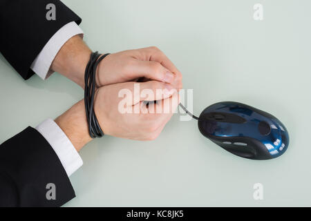 Close-up Of Person Wrist Tied With Computer Mouse Cable Stock Photo