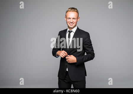 A confident elegant handsome young man standing in front of a grey background in a studio wearing a nice suit Stock Photo