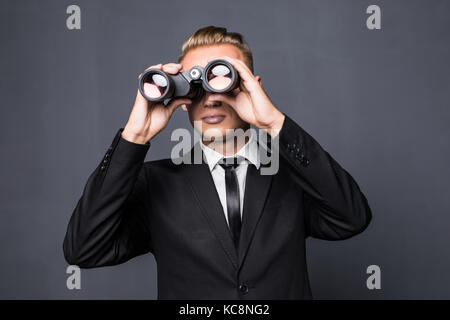 Handsome american businessman using binoculars in office on gray background Stock Photo